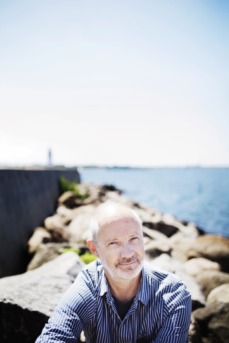 porträttbild av Fredrik Tjulander sittandes på klippor vid havet, vid en pir.