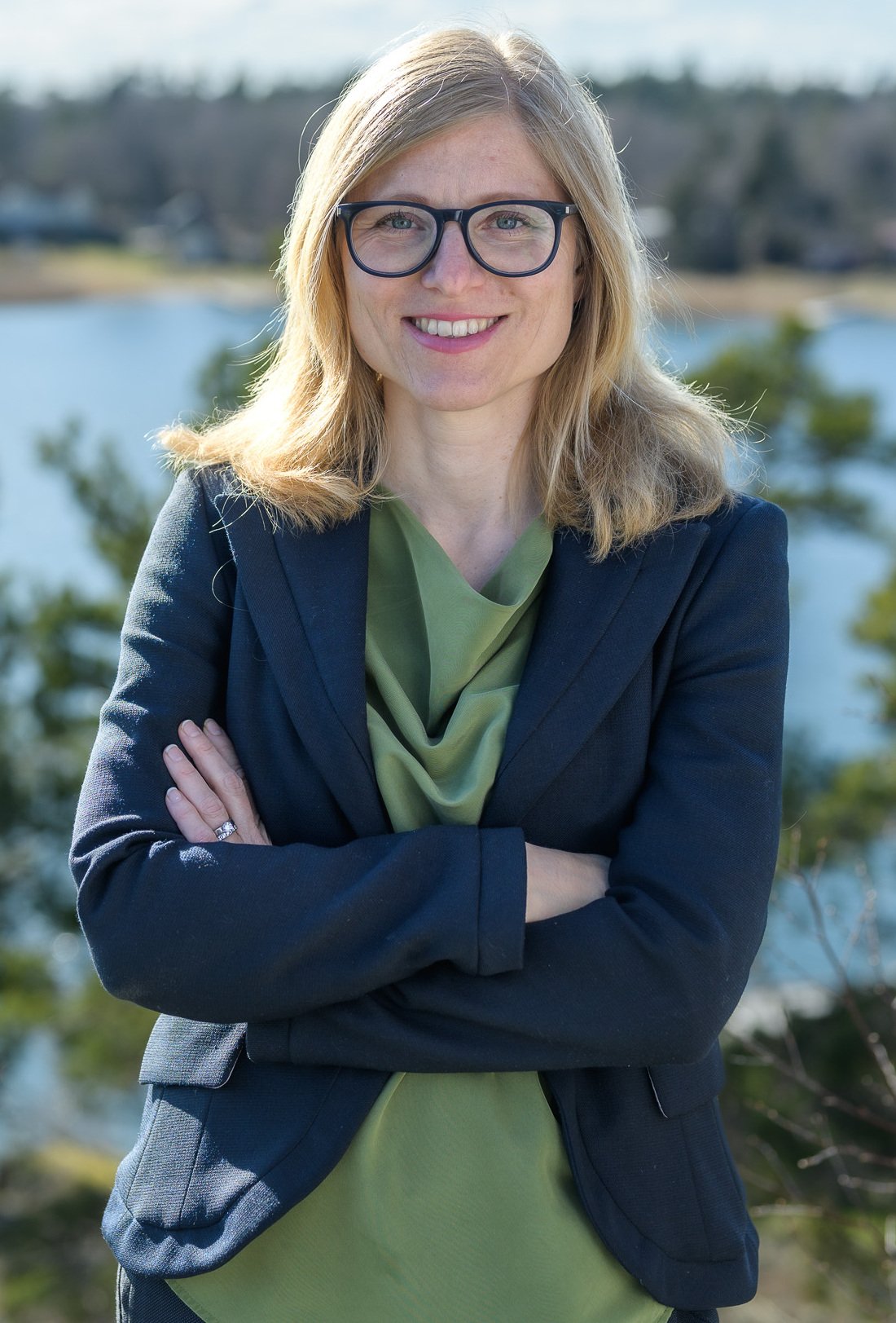 Porträtt av Kajsa Söderhielm, doktorand vid avdelningen för arbetsterapi, NVS, taget ute i naturen med grönska och vatten i bakgrunden..