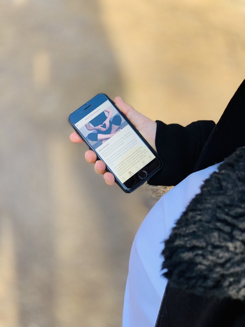 A pregnant woman looking at the HealthyMoms app on her phone (in her hand)
