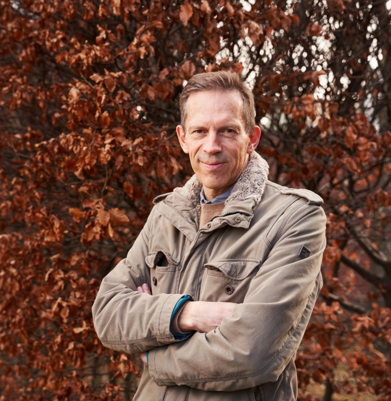 Thomas Perlmann outdoors, in front of a colorful deciduous tree.