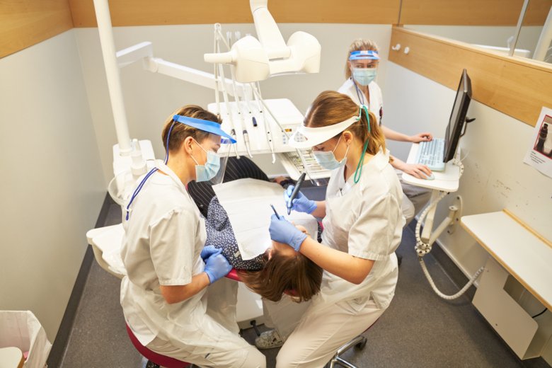 Två tandläkarstudenter utför undersökning på patient.