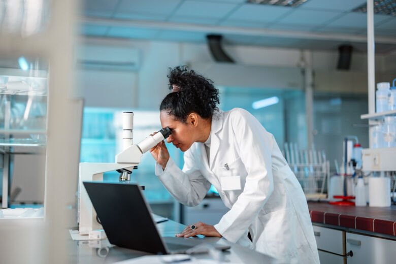Forskare i labbrock tittar i ett mikroskop.