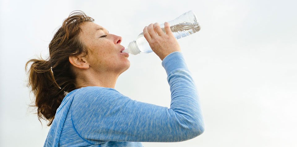 Kvinna som dricker vatten ur flaska