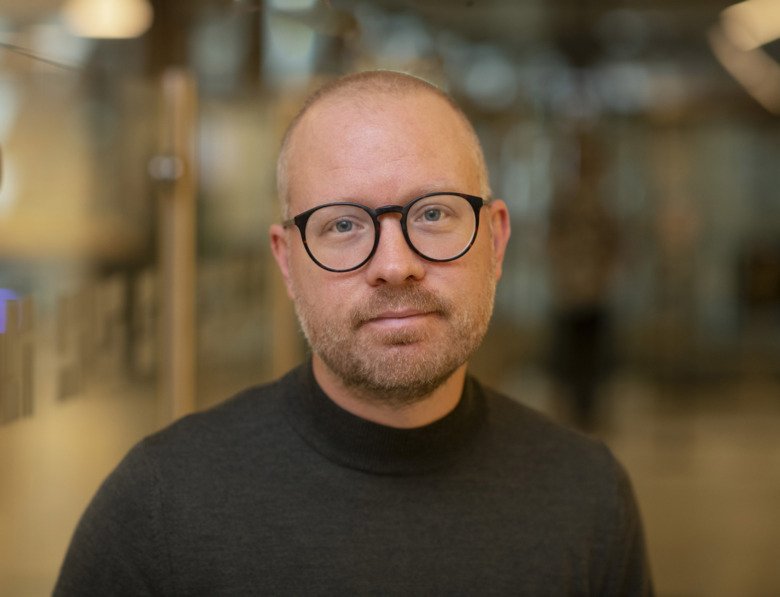 Porträttbild av Johan Åhlen med svarta runda glasögon.