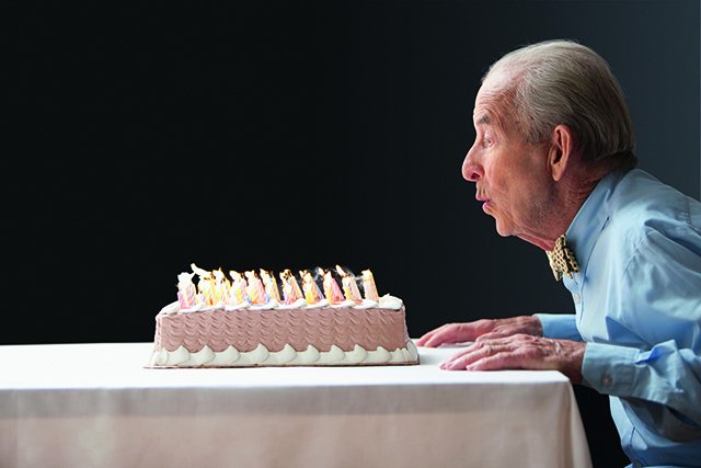 Old man blowing out birthday candles