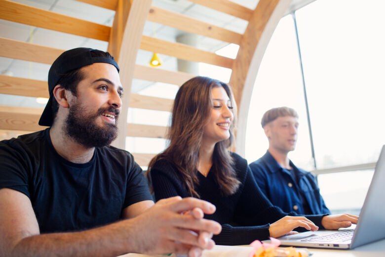 Three students sitting at a table with a computer.