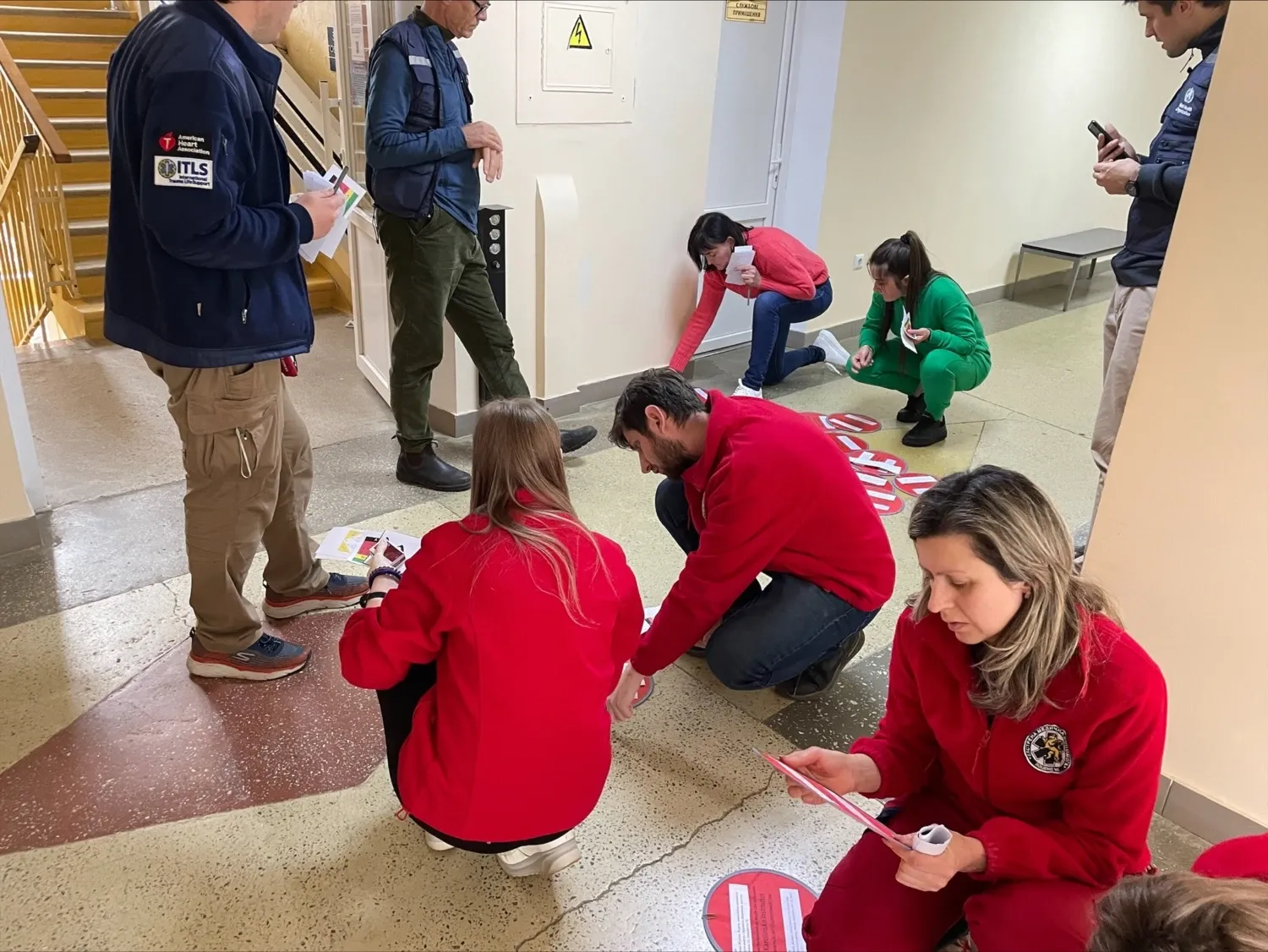 A group of people standing and sitting on the floor studying red plates