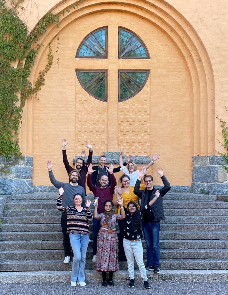 A group of happy people standing in the steps in front of a building.