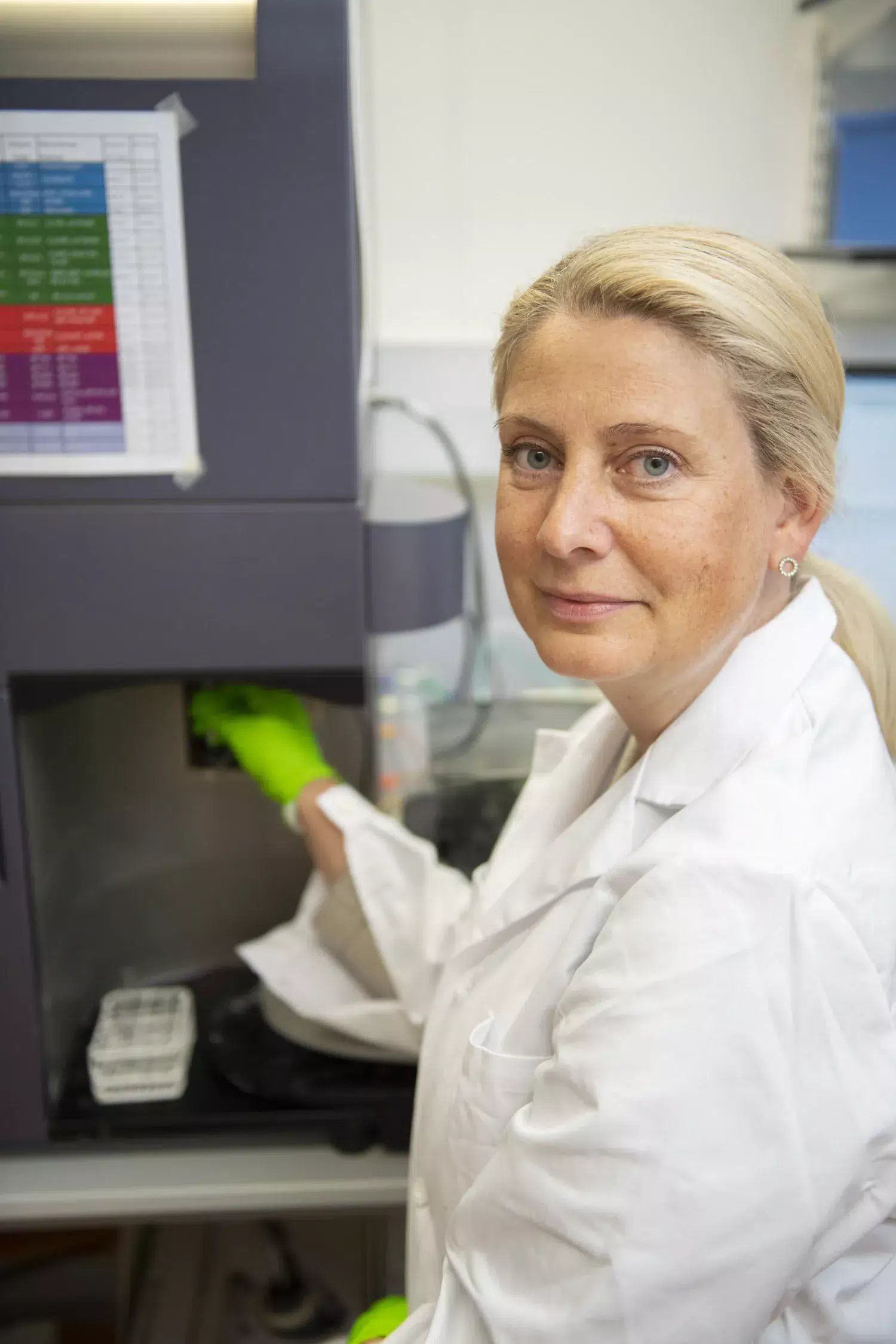 Porträtt av Anna Smed Sörensen i labbet. Hon är blond, har vit rock och gröna handskar.