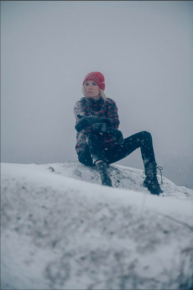 Bild på Bea Uusma utomhus i snön sittandes på ett berg.