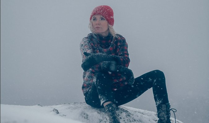 Bild på Bea Uusma utomhus i snön sittandes på ett berg.