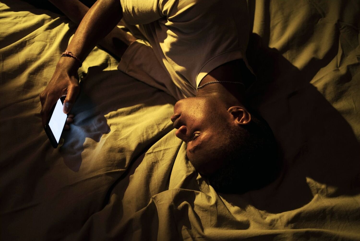 Man lying in bed scrolling his phone