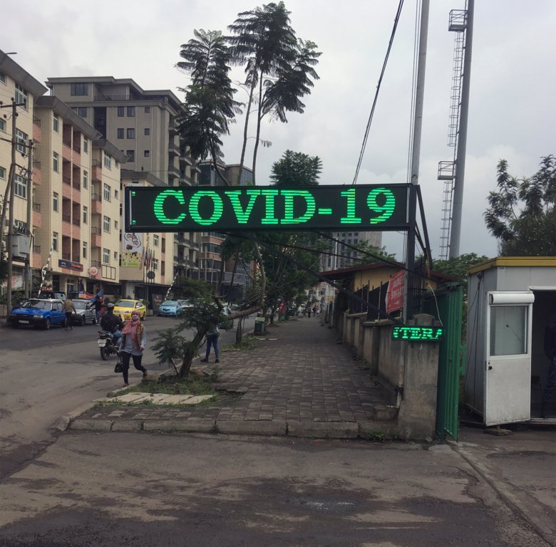 en gata utanför ett sjukhus i Addis Ababa i Etiopien med en stor grön neonskylt där det står covid-19