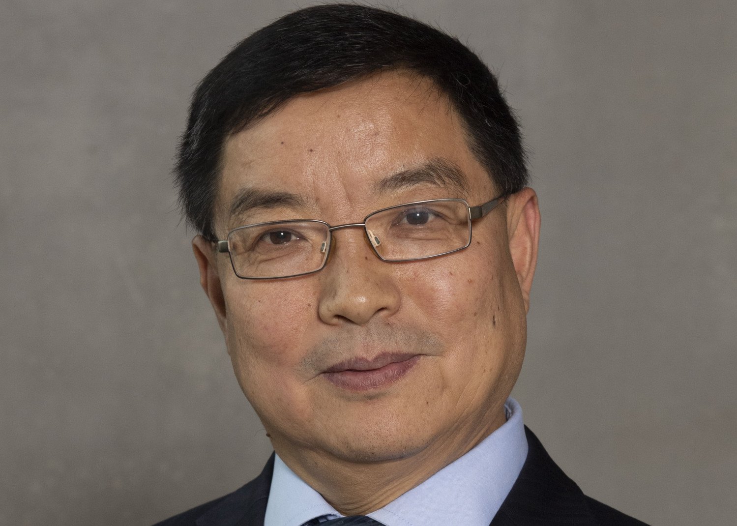 Portrait of Chengxuan Qiu, Aging Research Center (ARC), in suit, againt neutral background.