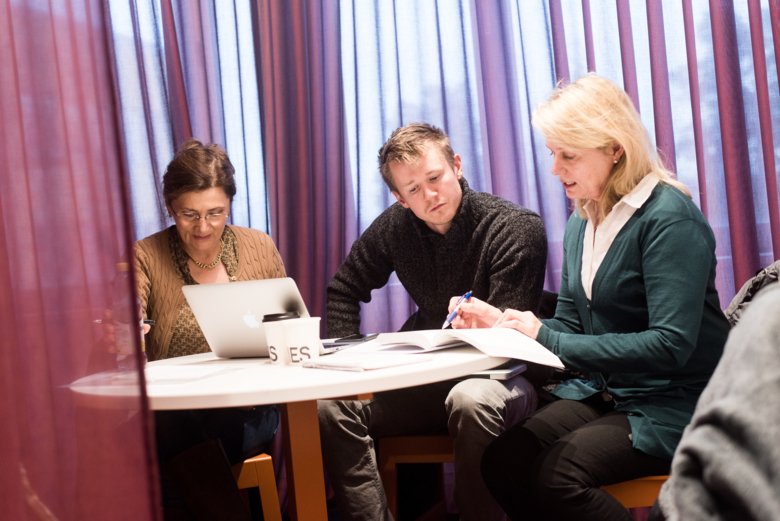 Three persons at a table are talking