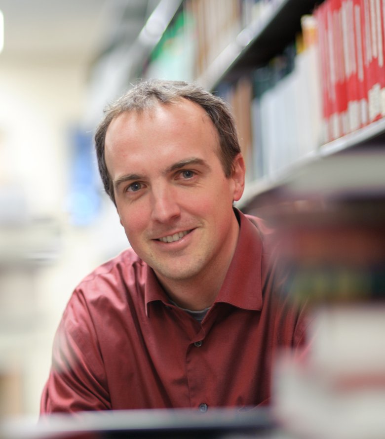 Professor Kevin Eva sitting behind a pile of books.