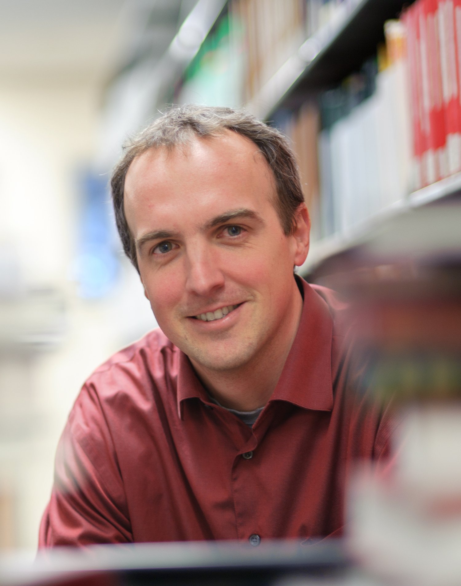 Professor Kevin Eva sitting behind a pile of books.