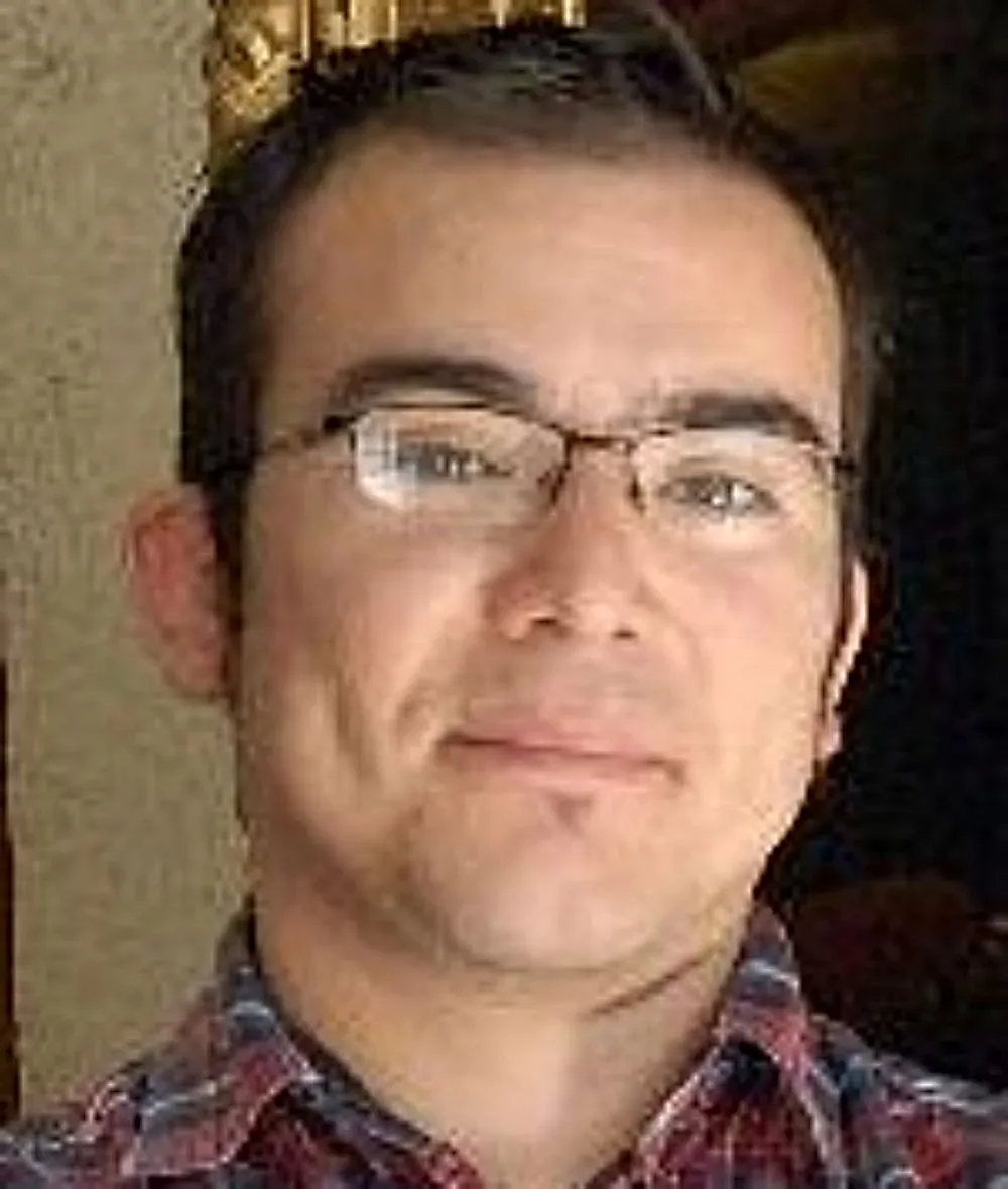 A man with glasses smiles to the camera