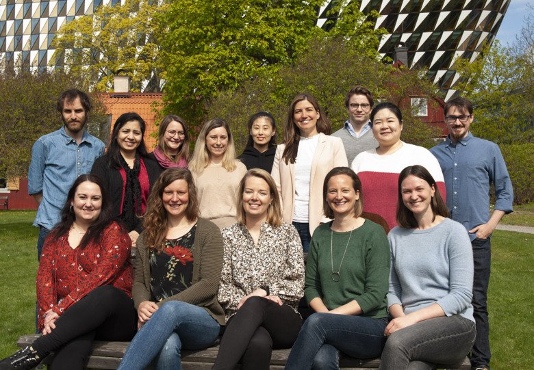 A group of people outside sitting and standing infront of the camera for a group portrait