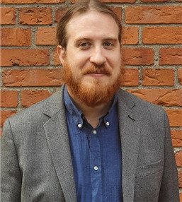 Porträtt av Erland Axelsson, anknuten forskare vid avdelningen för allmänmedicin och primärvård, NVS, framför röd tegelvägg..