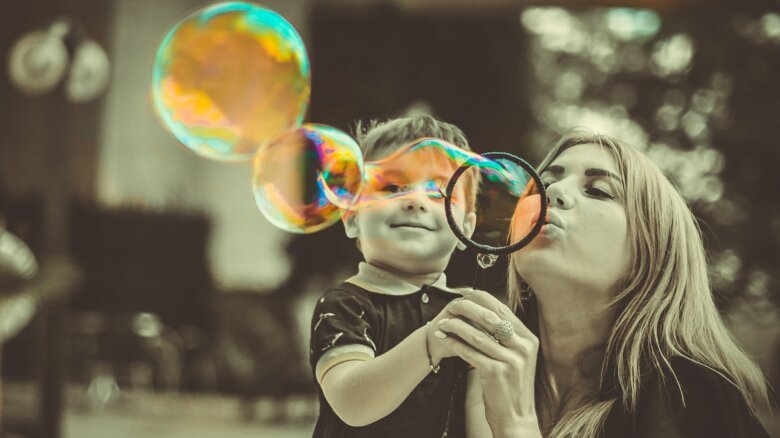 Mother blowing soap bubbles with her son.