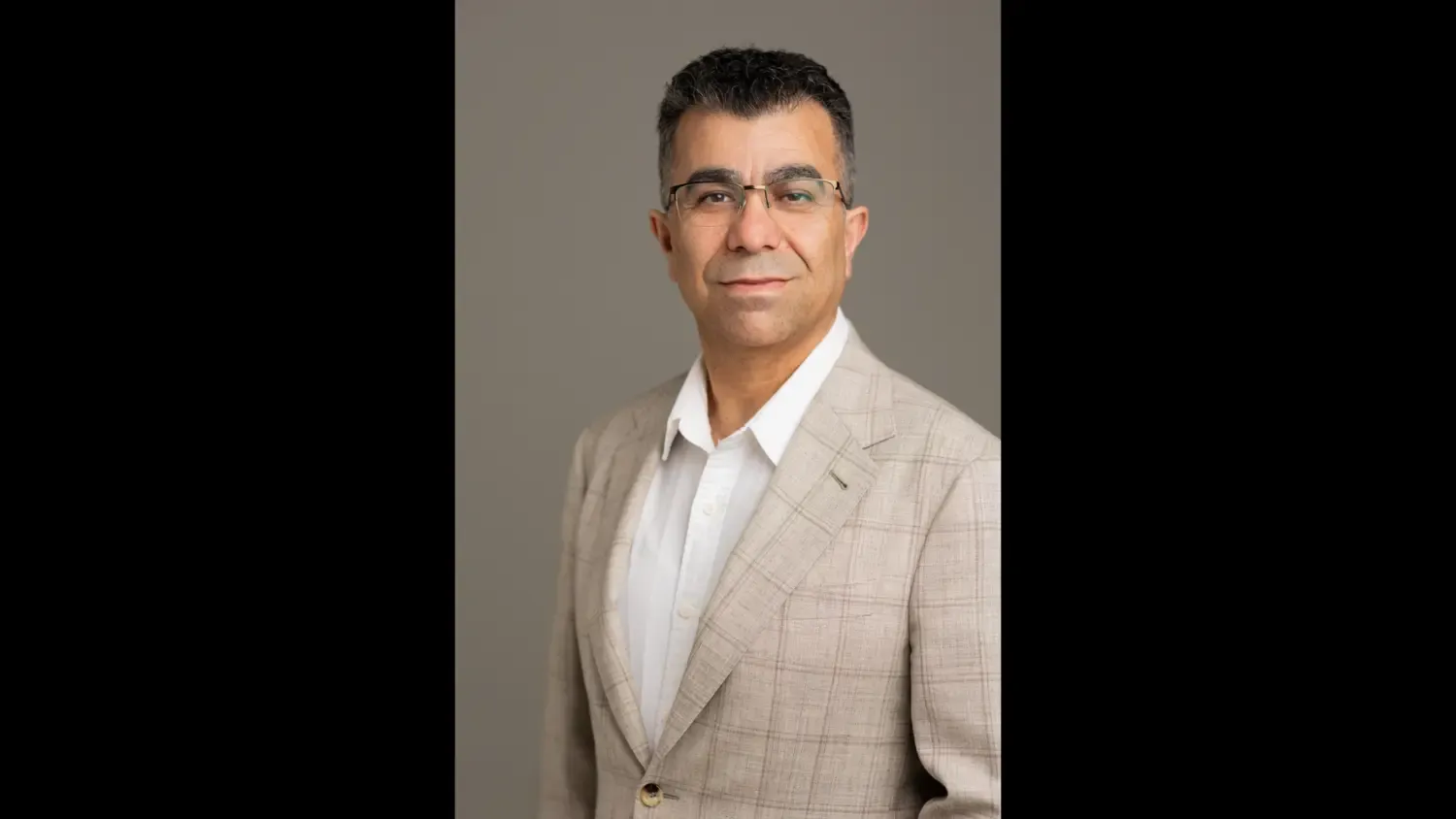Photo of a man with dark hair wearing a light suit jacket