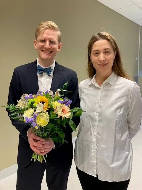 Foto av två personer, varav en av de håller i en stor blombukett.