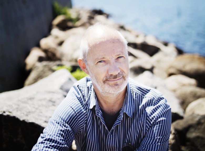 Portrait of Fredrik Tjulander sitting on rocks by the sea.