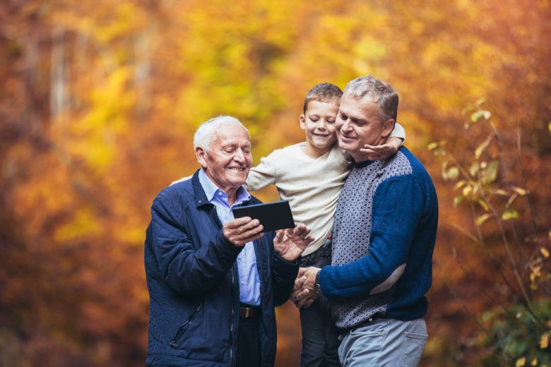 Äldre far vuxen son och barnbarn ut på en promenad i parken, med hjälp av digital tablett. - Bildbanksfoto
