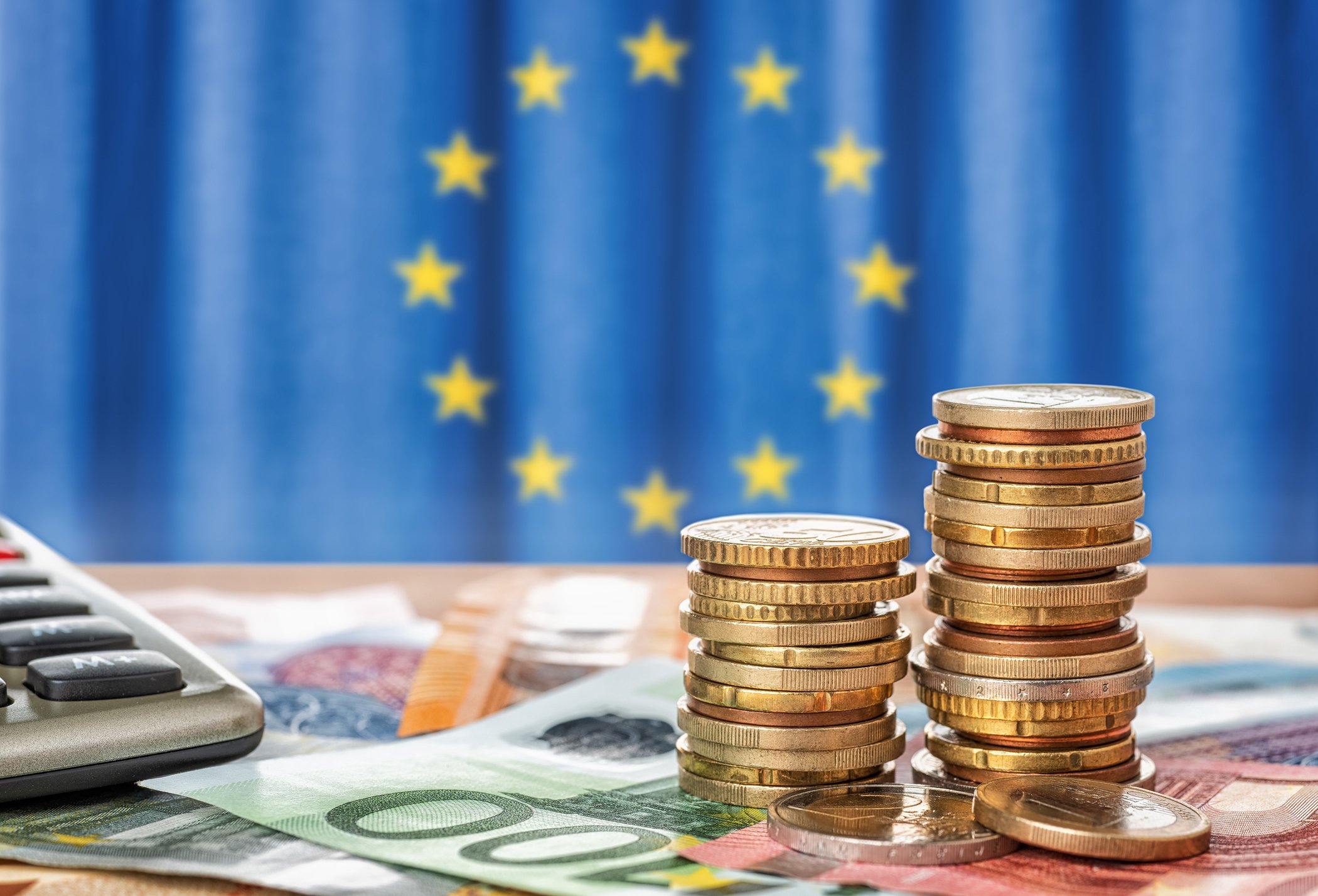 Sedlar och mynt framför Europeiska unionens flagga - Bildbanksfoto
