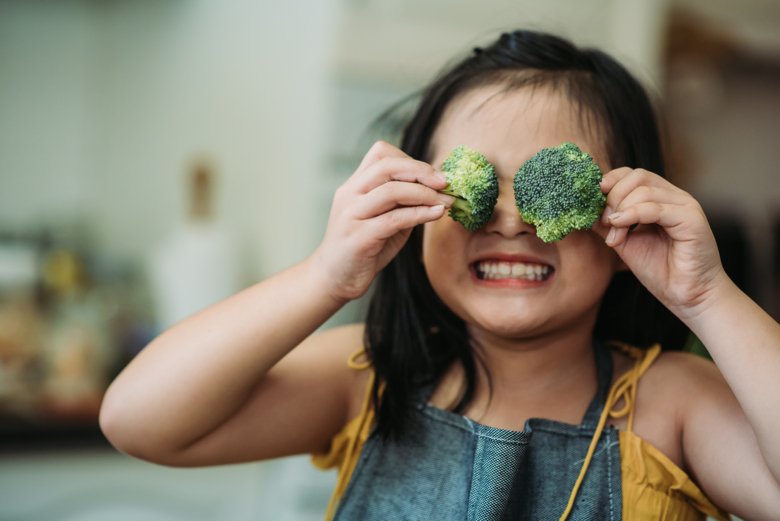 A girl with two broccolis in front of the eyes