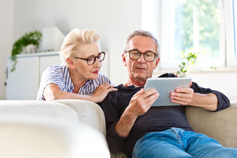 Senior par tittar på digital tablett tillsammans hemma - Bildbanksfoto.