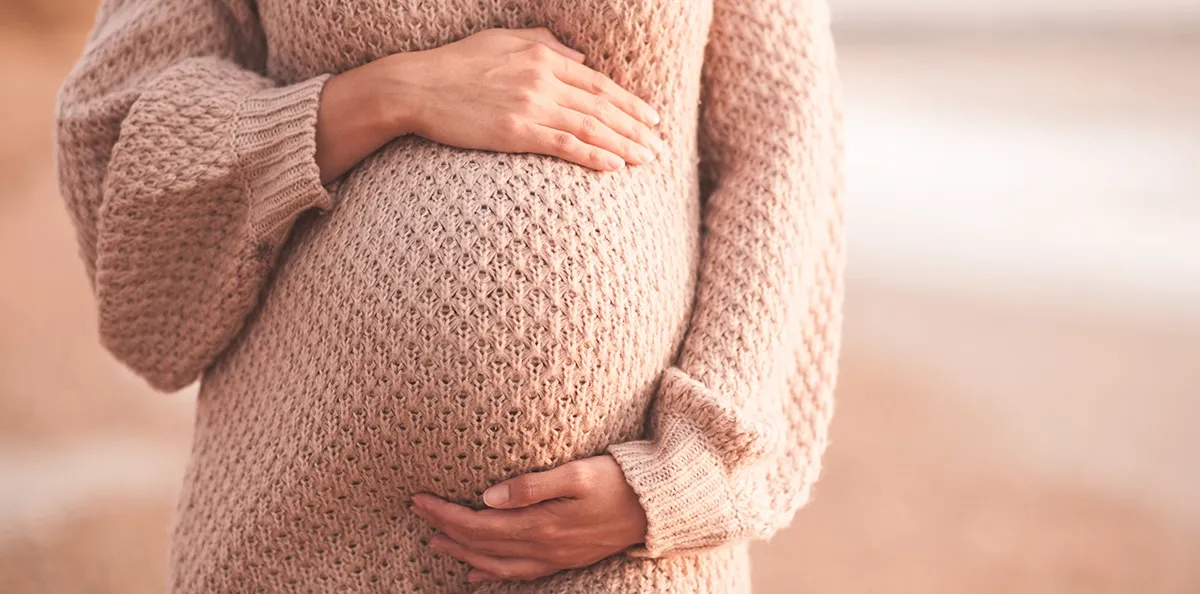 Dekorativ bild av en gravid kvinna i en stickad tröja
