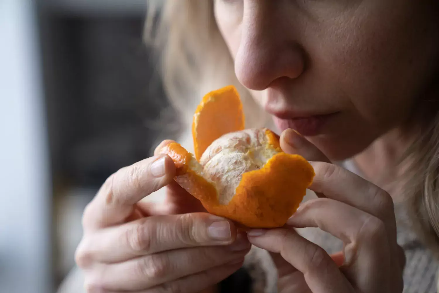 a women smelling a tangerine