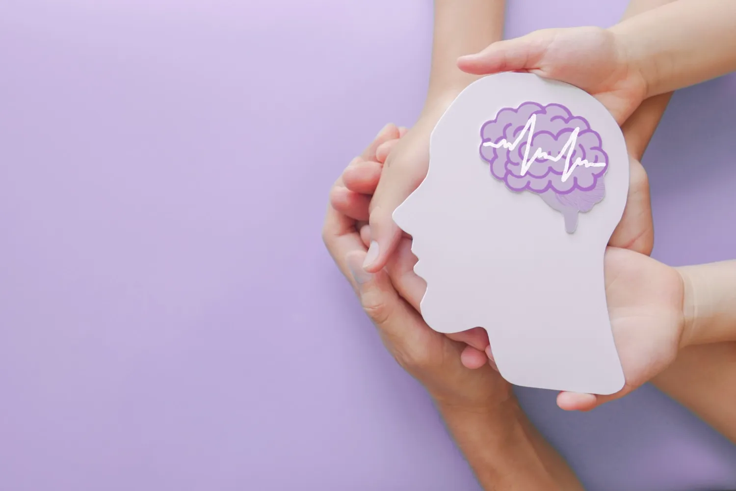 Adult and child hands holding encephalography brain paper cutout.