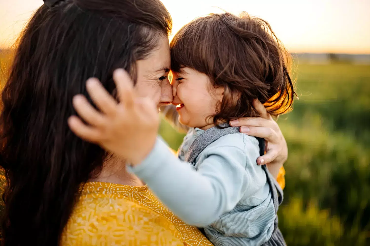 Mother and child cuddling outdoors.