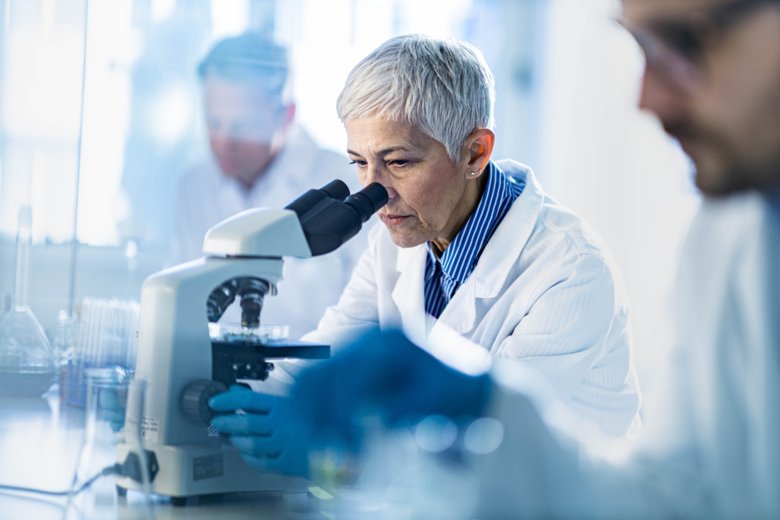 Woman with gray hair looking in to a microscope