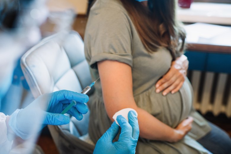 Pregnant woman sitting on a chair vaiting for a vaccine.