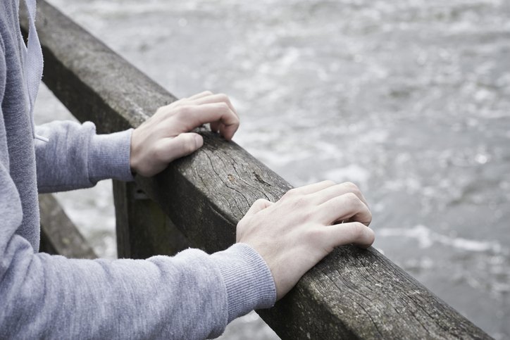 Depressed Young Man Contemplating Suicide On Bridge