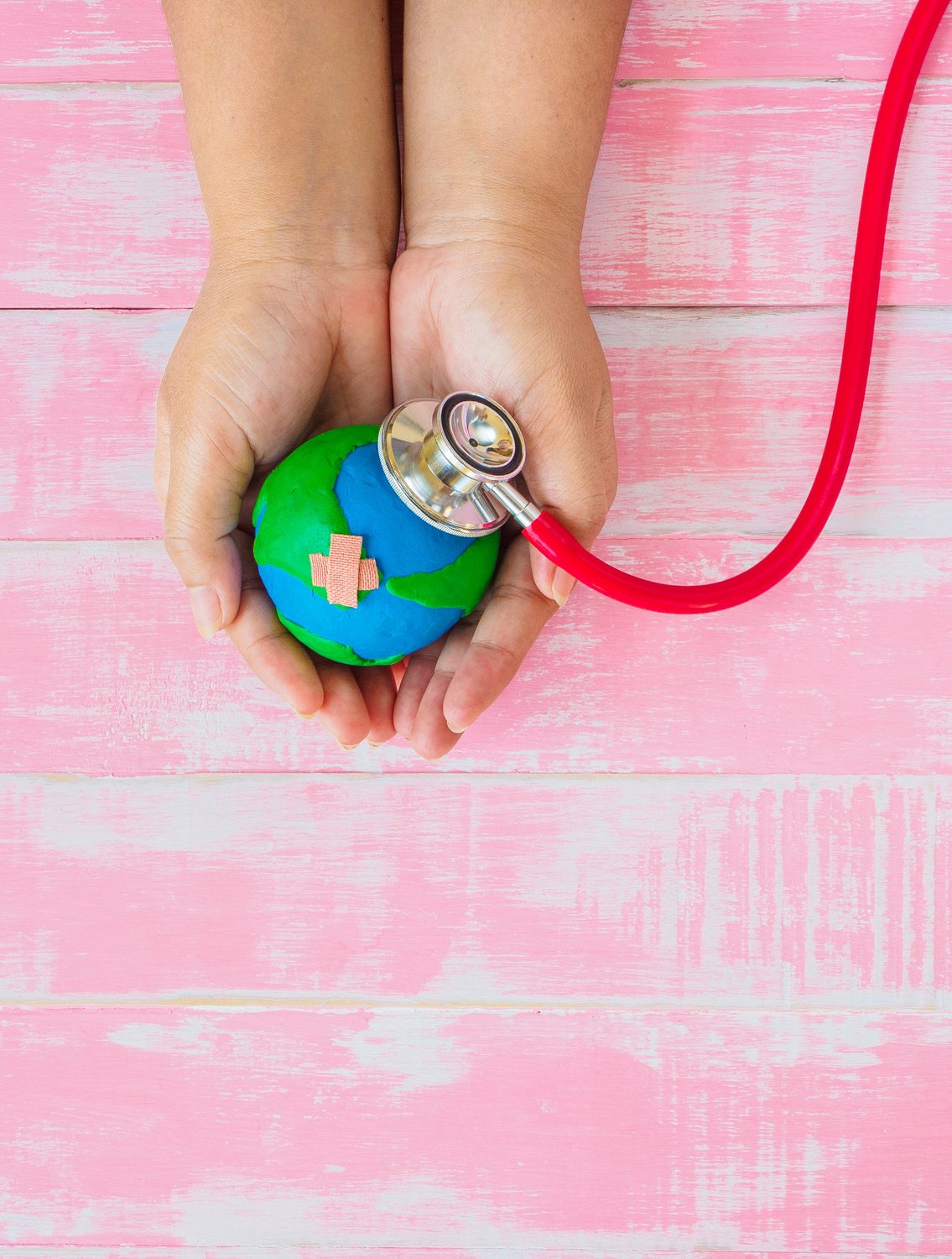 Symbolic illustration: hands holding a globe, which is being examined with a stethoscope.