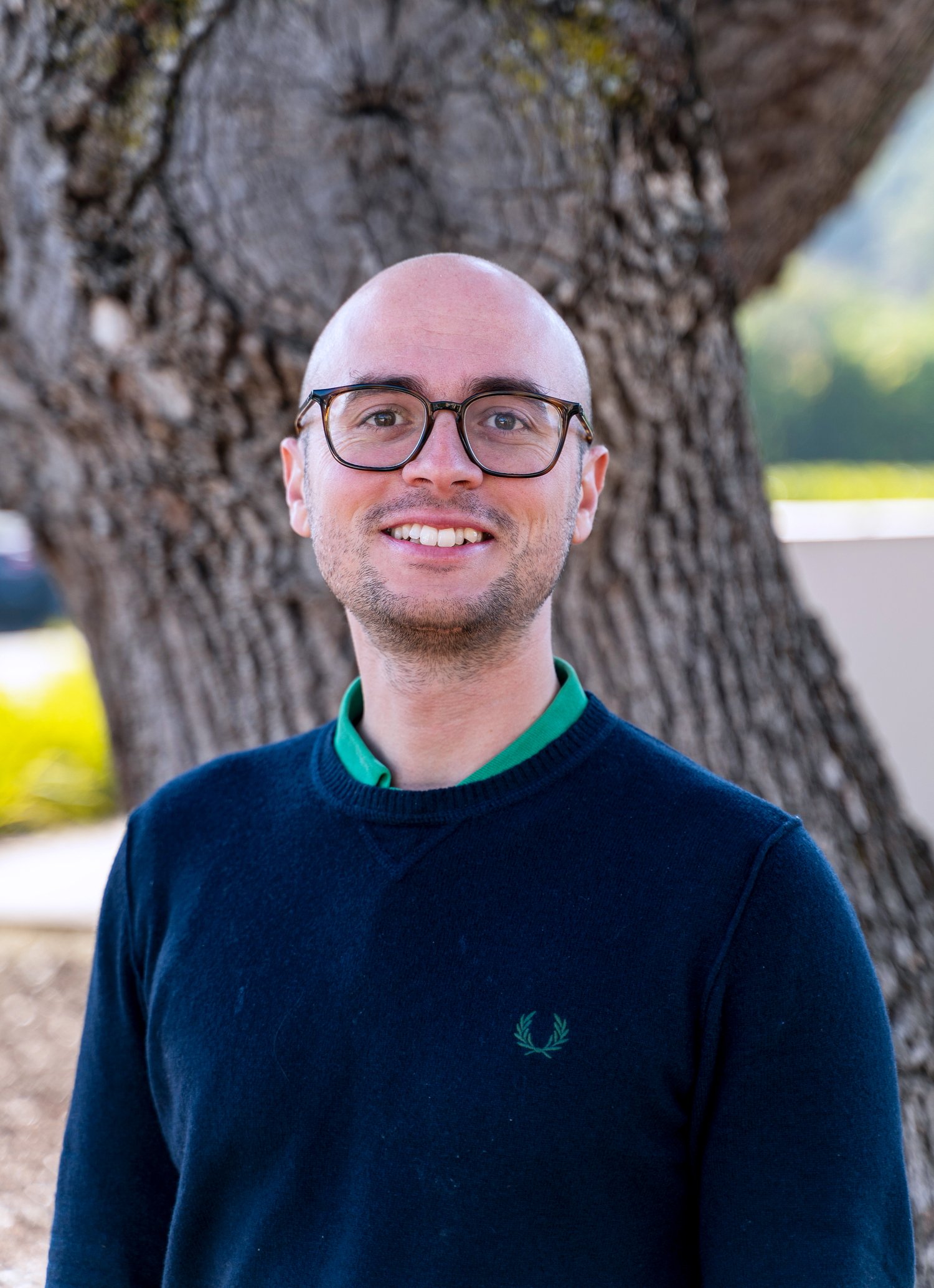 Portrait in front of a tree trunk.