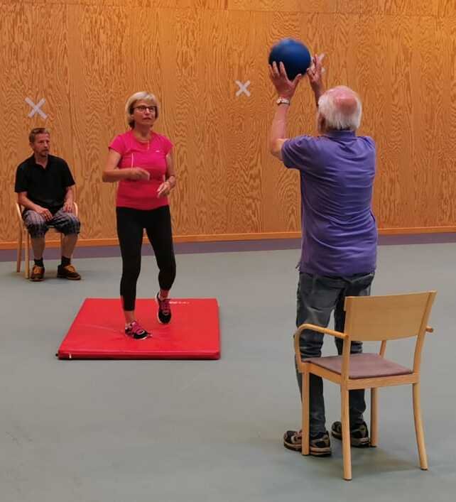 People standing or sitting in a ring, throwing a ball to each other.