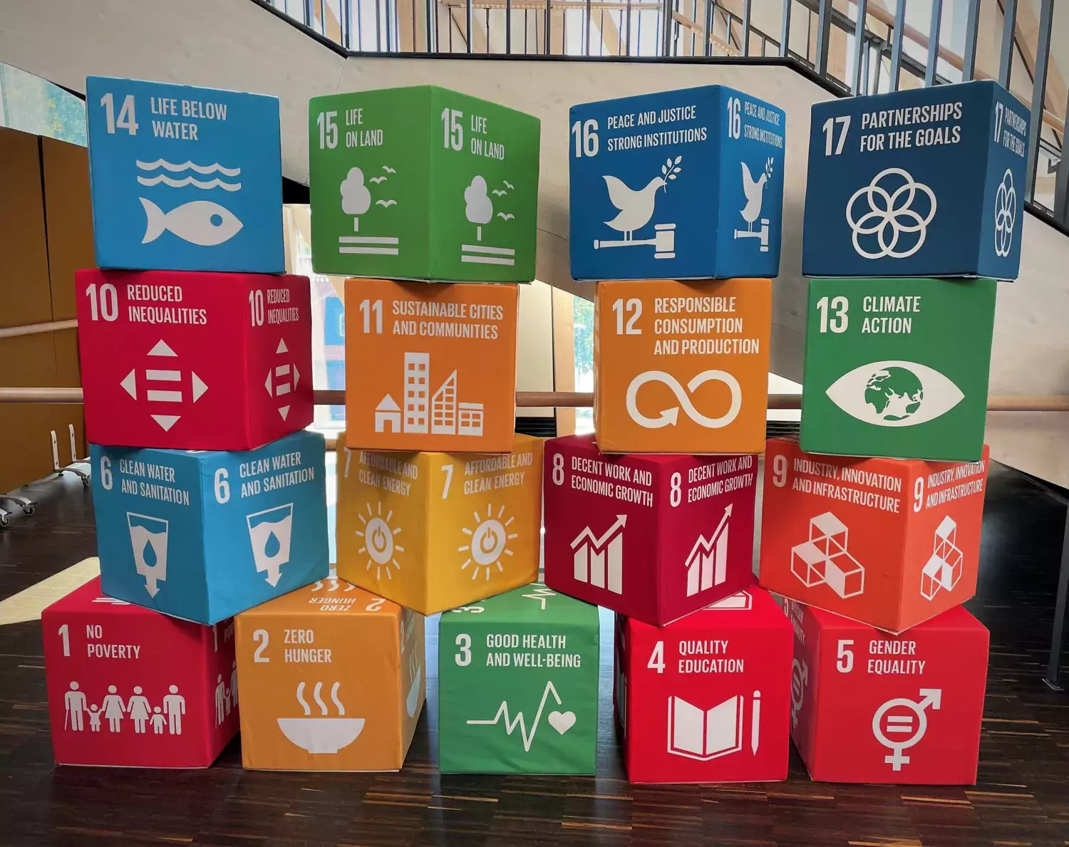 Staplade lådor med symboler för olika hållbarhetsområden enligt Agenda 2030.