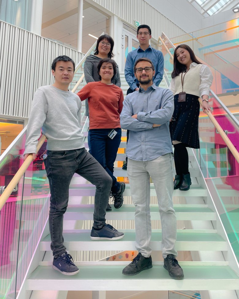 Hong Qians forskargrupp står i ett ljust och färgglatt trapphus
