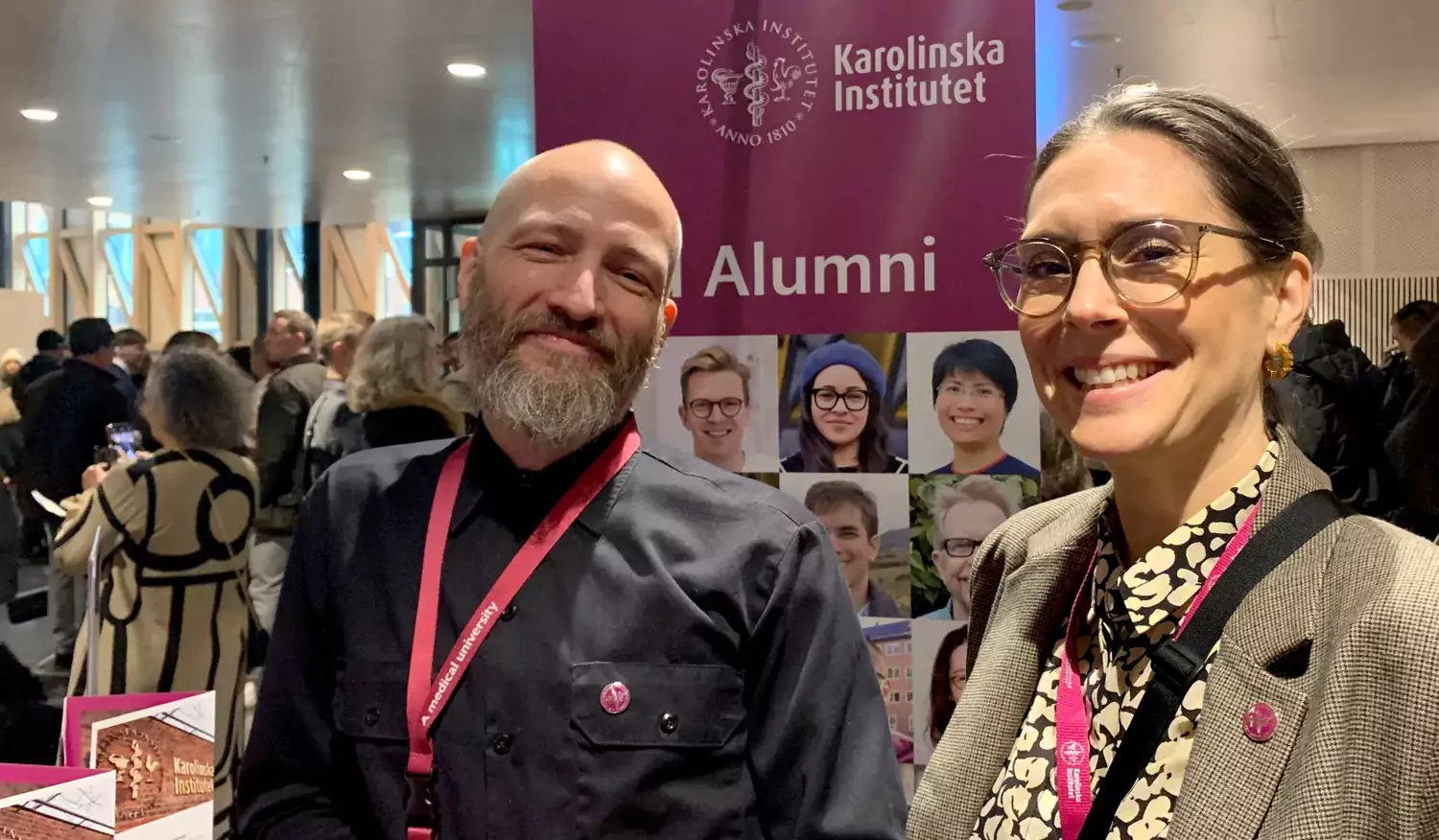 Two people in front of a KI Alumni roll-up.
