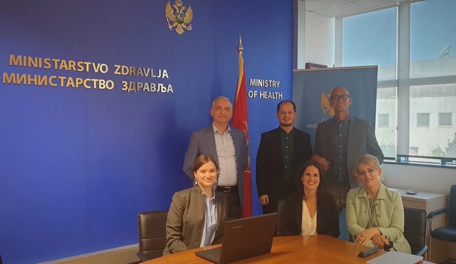 People standing in front of a blue wall with the text Ministry of Health