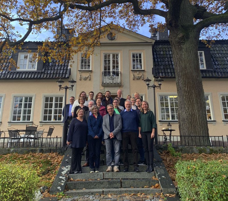 Photo of group of people on top of stairs in front of a buliding.