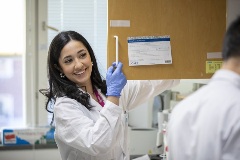 Woman in lab smiling and talking to another researcher.