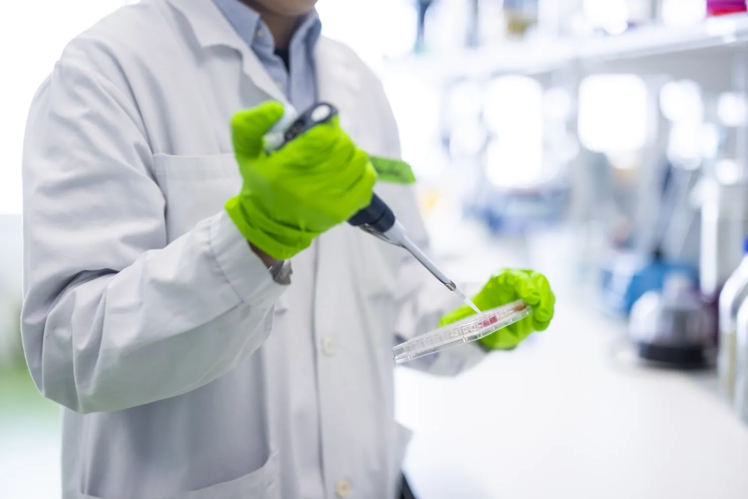 Hands working with pipette and test tubes.