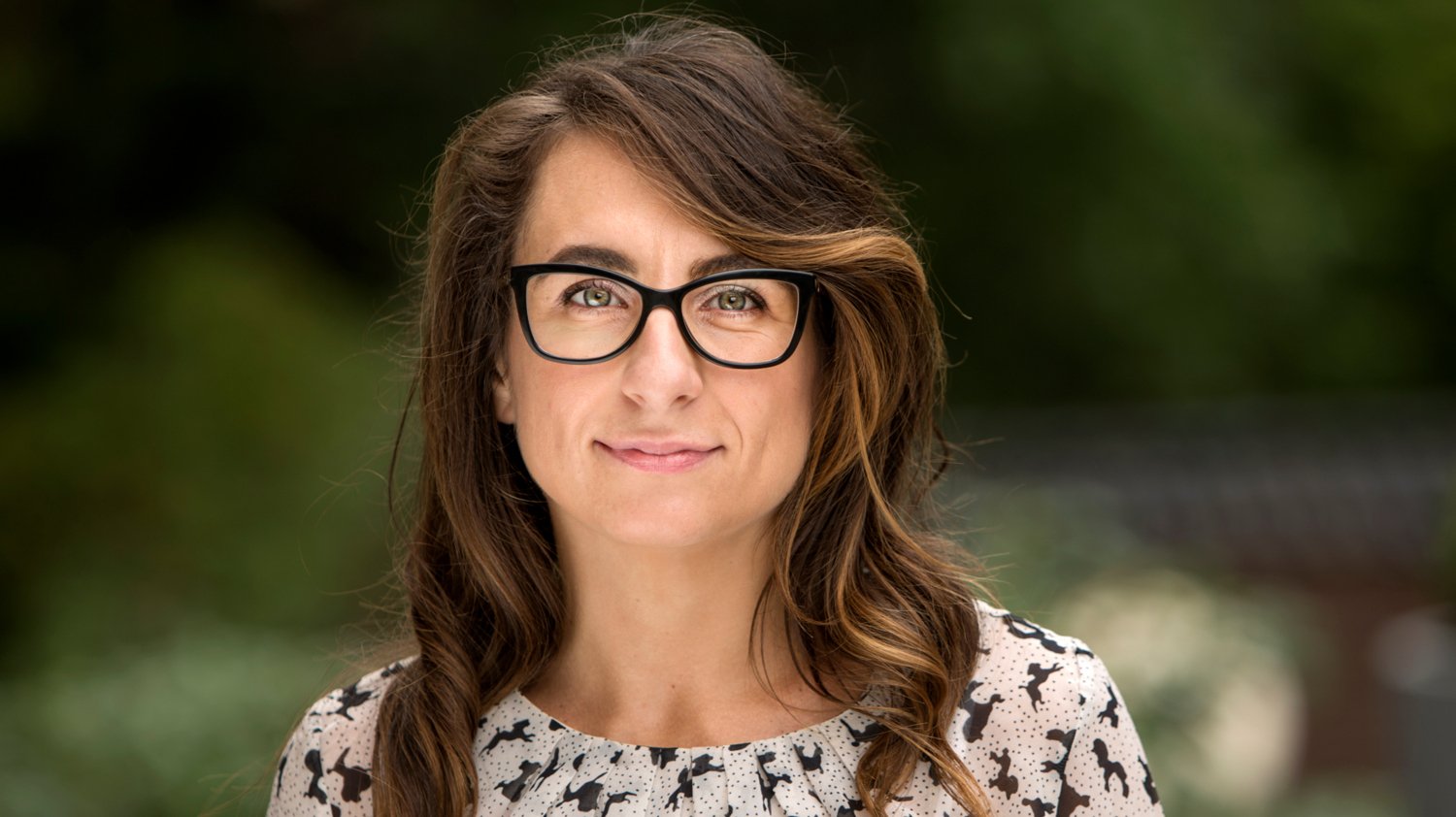 Portrait of a women with dark hair and glasses.